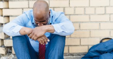 ethnic male sorrowing near wall on street man knee stress depression