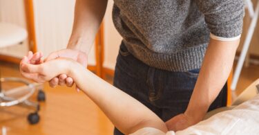 crop chiropractor massaging hand of patient