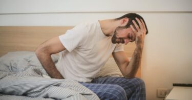 young man in sleepwear suffering from headache in morning