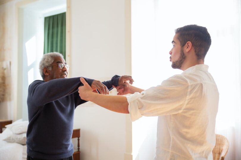 an elderly man talking to the man in white shirt while holding hands