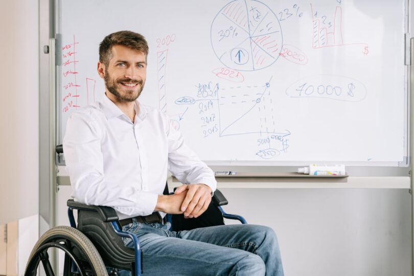 a man smiling next to a whiteboard
