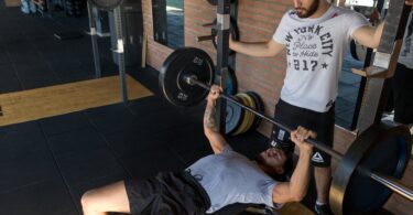 man lying while doing barbell