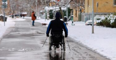 a man in a wheelchair on a road during winter
