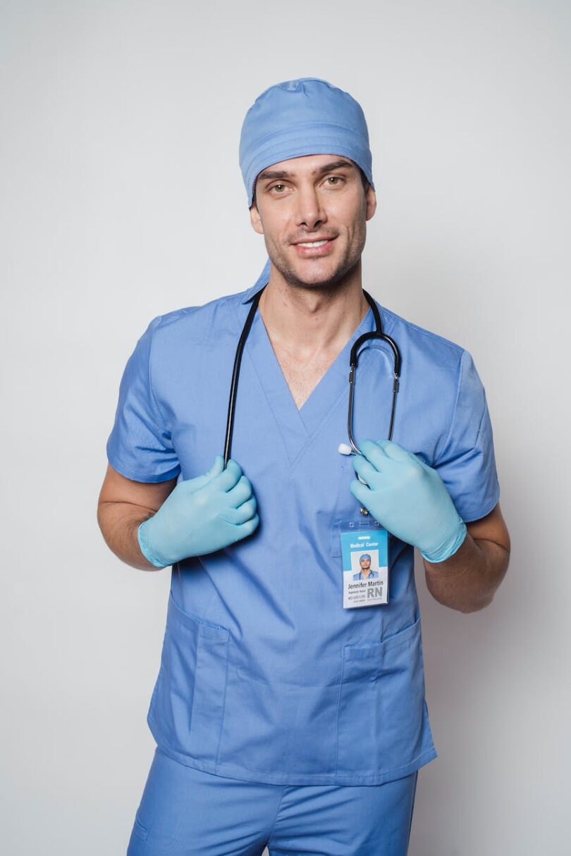 cheerful man doctor in uniform standing with stethoscope in light room