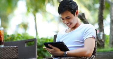 man in white shirt using tablet computer shallow focus photography