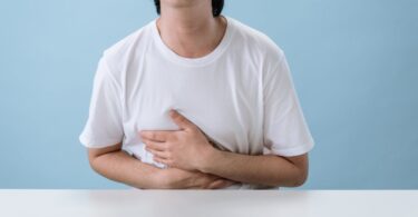 man in white shirt suffering from a stomach pain