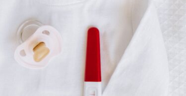 pregnancy test kit beside a pacifier