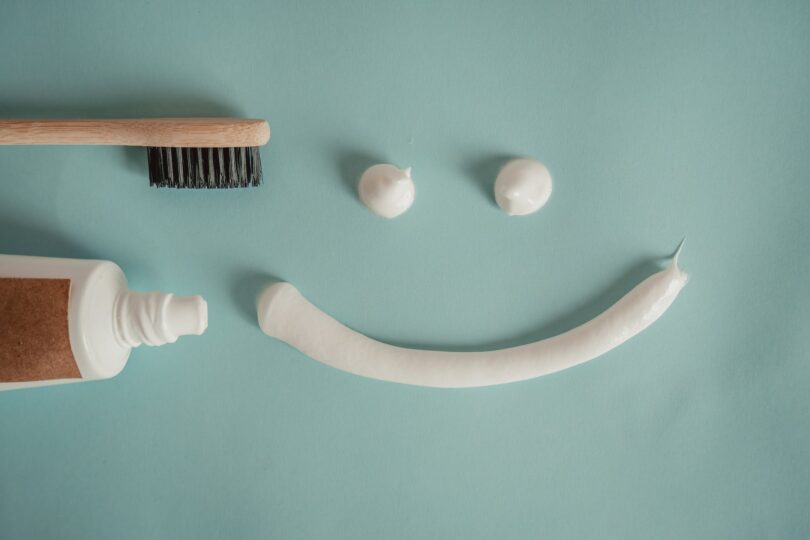 toothbrush a a tube of toothpaste and a smile painted with toothpaste