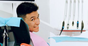 cheerful ethnic man sitting in dental chair in modern dentist office