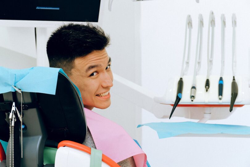 cheerful ethnic man sitting in dental chair in modern dentist office