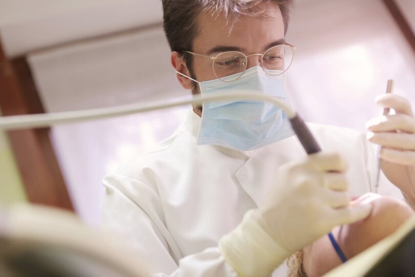 man in white dress shirt holding dental tools