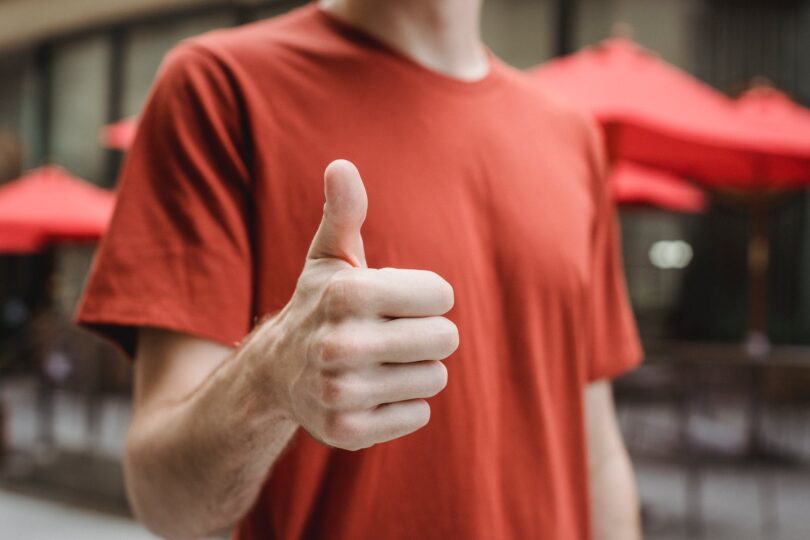 unrecognizable man showing thumb up on city street