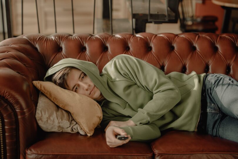 person in brown robe lying on brown leather couch