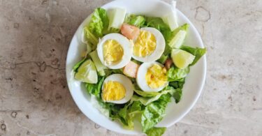 fresh vegetable salad with boiled eggs on white ceramic plate