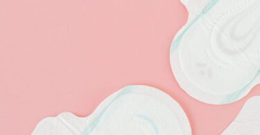 white and blue sanitary napkins on pink surface
