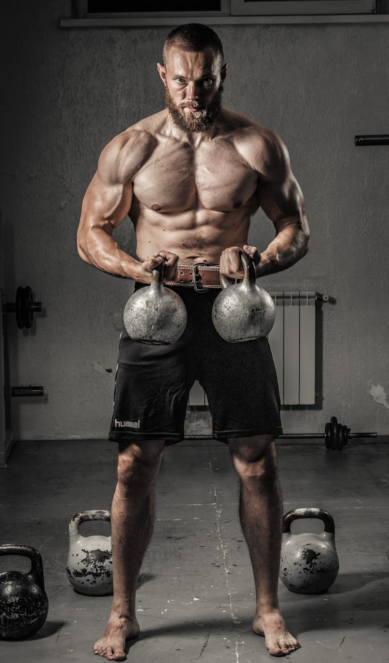 man in black shorts holding black kettle bell