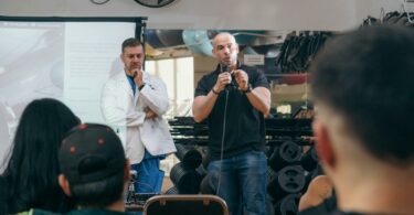 man giving a speech at the gym accompanied by a doctor