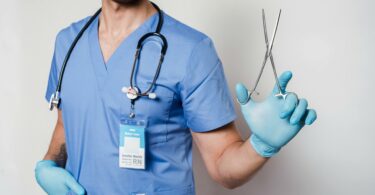 anonymous doctor in uniform and gloves with stethoscope and forceps