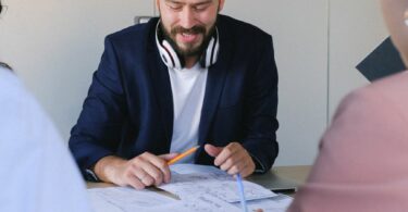 happy man with colleagues analyzing information in documents